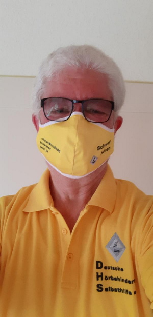 Mensch mit DHS-Mund-Nasen-Schutz in gelb und gelbem DHS-Shirt